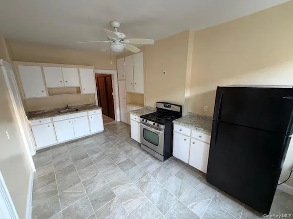 a kitchen with granite countertop a refrigerator and a stove top oven