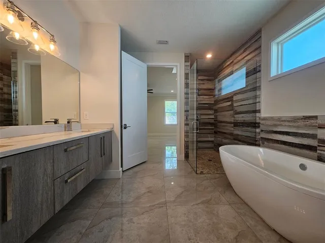 a spacious bathroom with a double vanity sink a large mirror and a bathtub