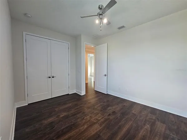 an empty room with wooden floor and ceiling fan