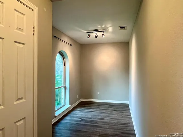a view of an empty room with wooden floor and a window