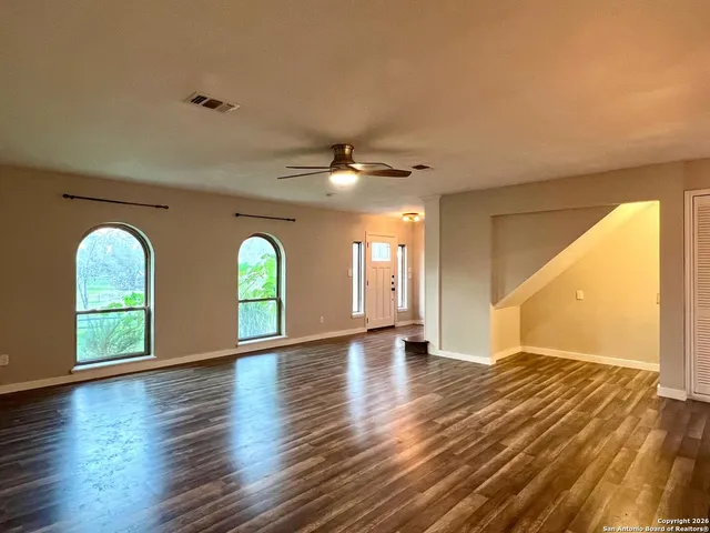 a view of an empty room with window and wooden floor