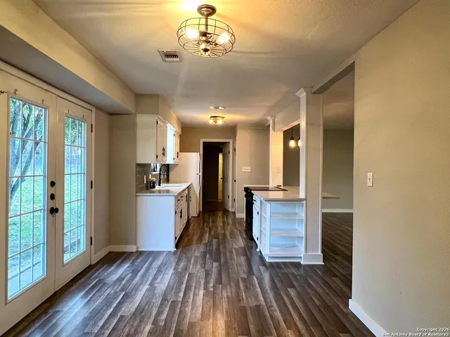 a view of a hallway with wooden floor and a kitchen