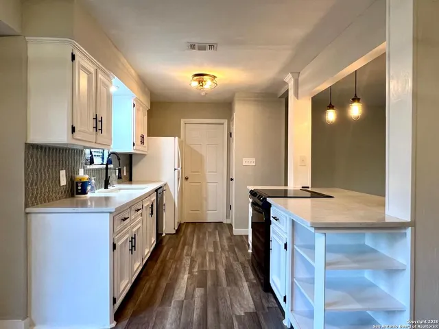 a kitchen with granite countertop a sink stove refrigerator and cabinets