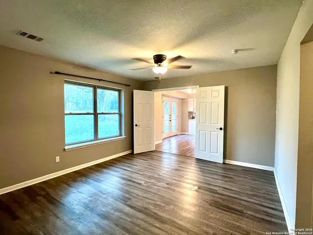 a view of an empty room with window and wooden floor