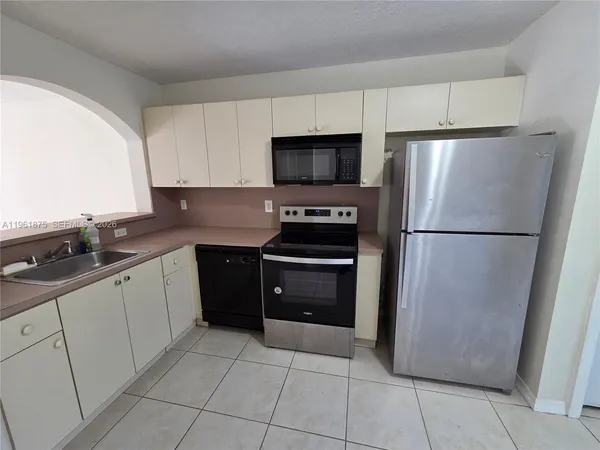 a kitchen with a refrigerator sink and cabinets