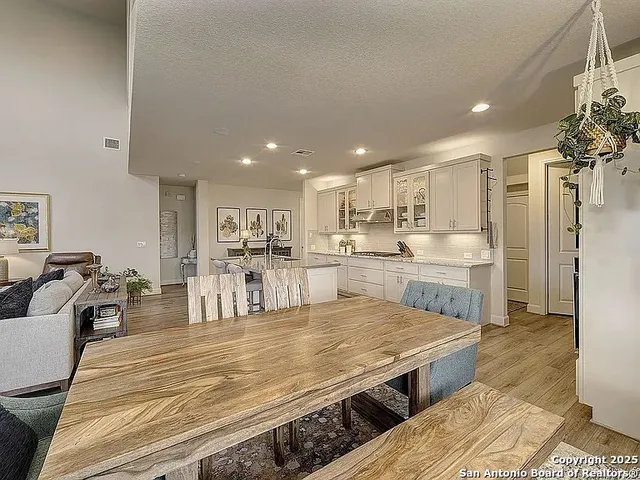 a large kitchen with kitchen island a stove a sink dishwasher and white cabinets with wooden floor