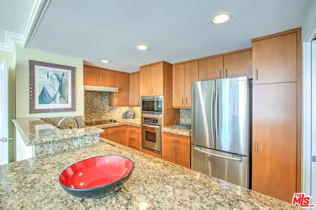 a kitchen with stainless steel appliances granite countertop a refrigerator and a stove