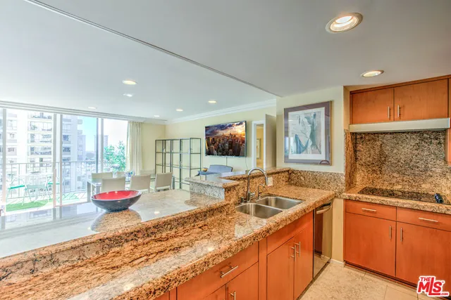 a open kitchen with stainless steel appliances granite countertop a stove top oven a dining table and chairs with wooden floor