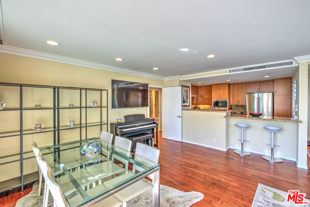 2160 Century Park East, Unit 1607 Los Angeles, CA 90067 - Photo 19 of 38 a open kitchen with stainless steel appliances granite countertop a stove top oven a dining table and chairs with wooden floor