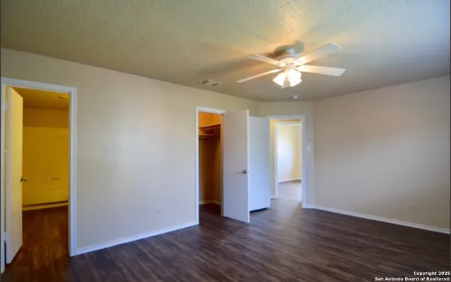 an empty room with wooden floor and a ceiling fan