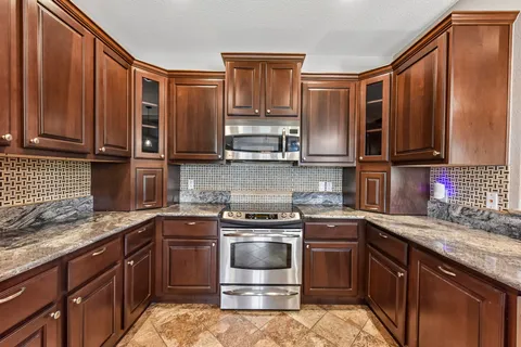 a kitchen with stainless steel appliances granite countertop a sink stove and refrigerator