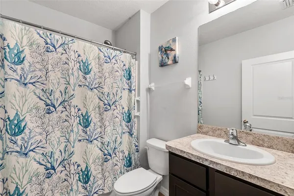 a bathroom with a granite countertop sink a toilet and a mirror