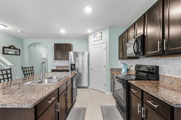a kitchen with stainless steel appliances granite countertop a sink a stove and a refrigerator