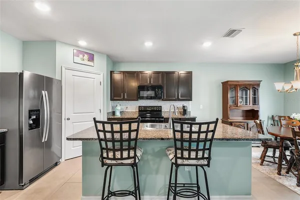 a view of a dining room with furniture a kitchen and chandelier