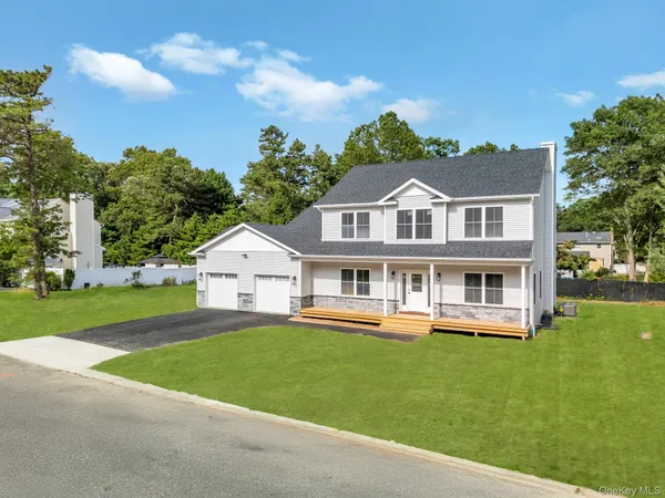 a front view of a house with a garden and lake view