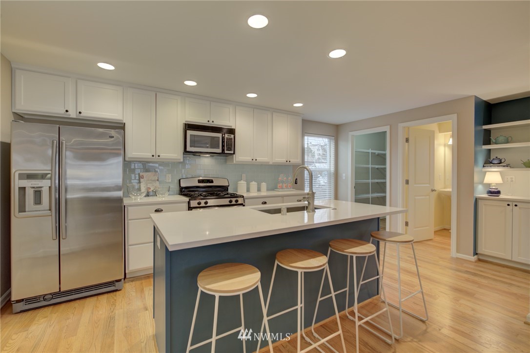 10136 Holman Road Northwest, Unit A Seattle, WA 98133 - Photo 3 of 27 a kitchen with stainless steel appliances granite countertop a stove a refrigerator a sink a dining table and chairs