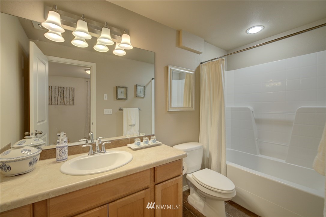 10136 Holman Road Northwest, Unit A Seattle, WA 98133 - Photo 22 of 27 a bathroom with a toilet a sink and a large mirror