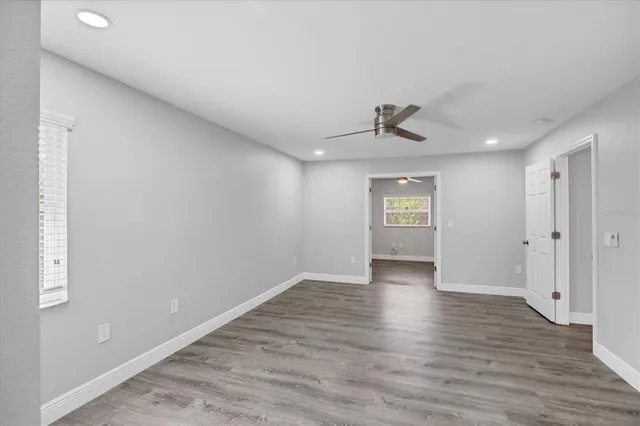 a view of an empty room with window and wooden floor