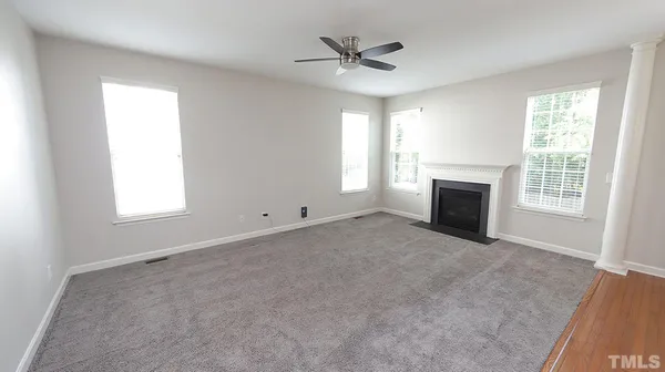 an empty room with windows and fireplace