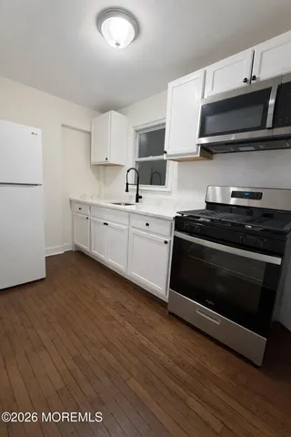 a kitchen with stainless steel appliances a stove a sink and white cabinets