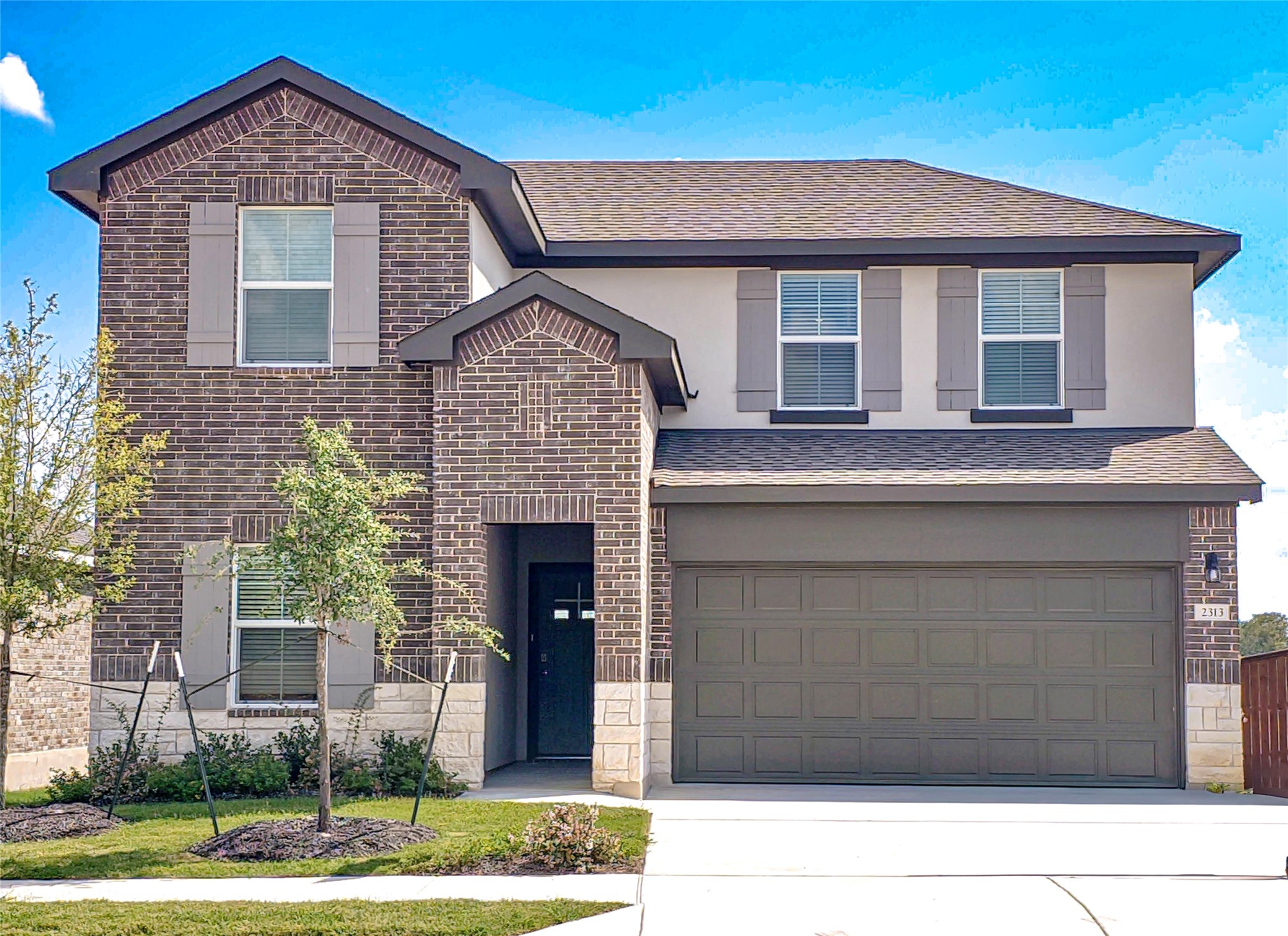 2313 March Hare Trace Leander, TX 78641 - Photo 1 of 30 View of front of property featuring brick siding, driveway, a shingled roof, a garage, and stucco siding