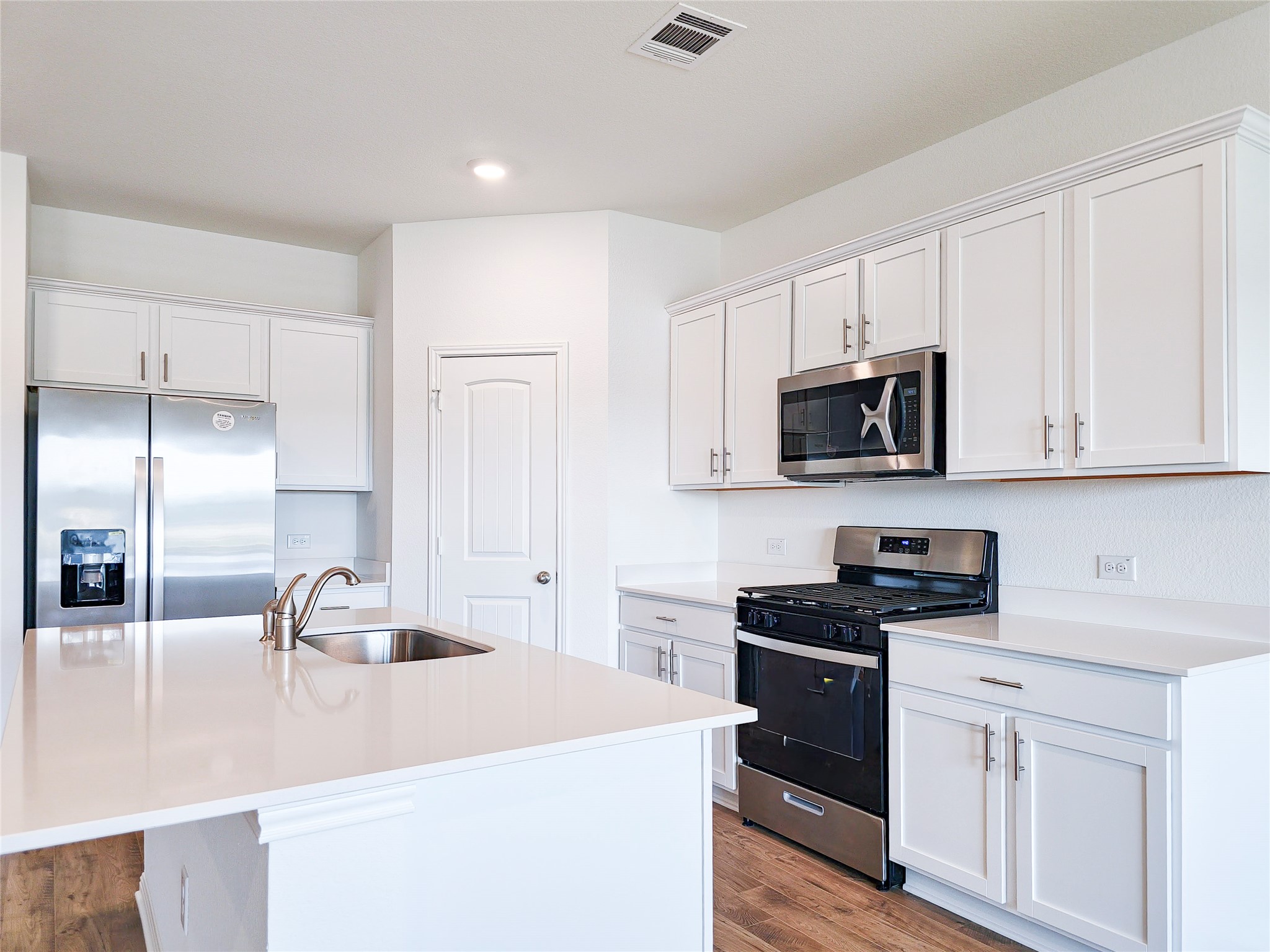 2313 March Hare Trace Leander, TX 78641 - Photo 14 of 30 Kitchen featuring stainless steel appliances, white cabinetry, a center island with sink, light wood-style floors, and light stone countertops