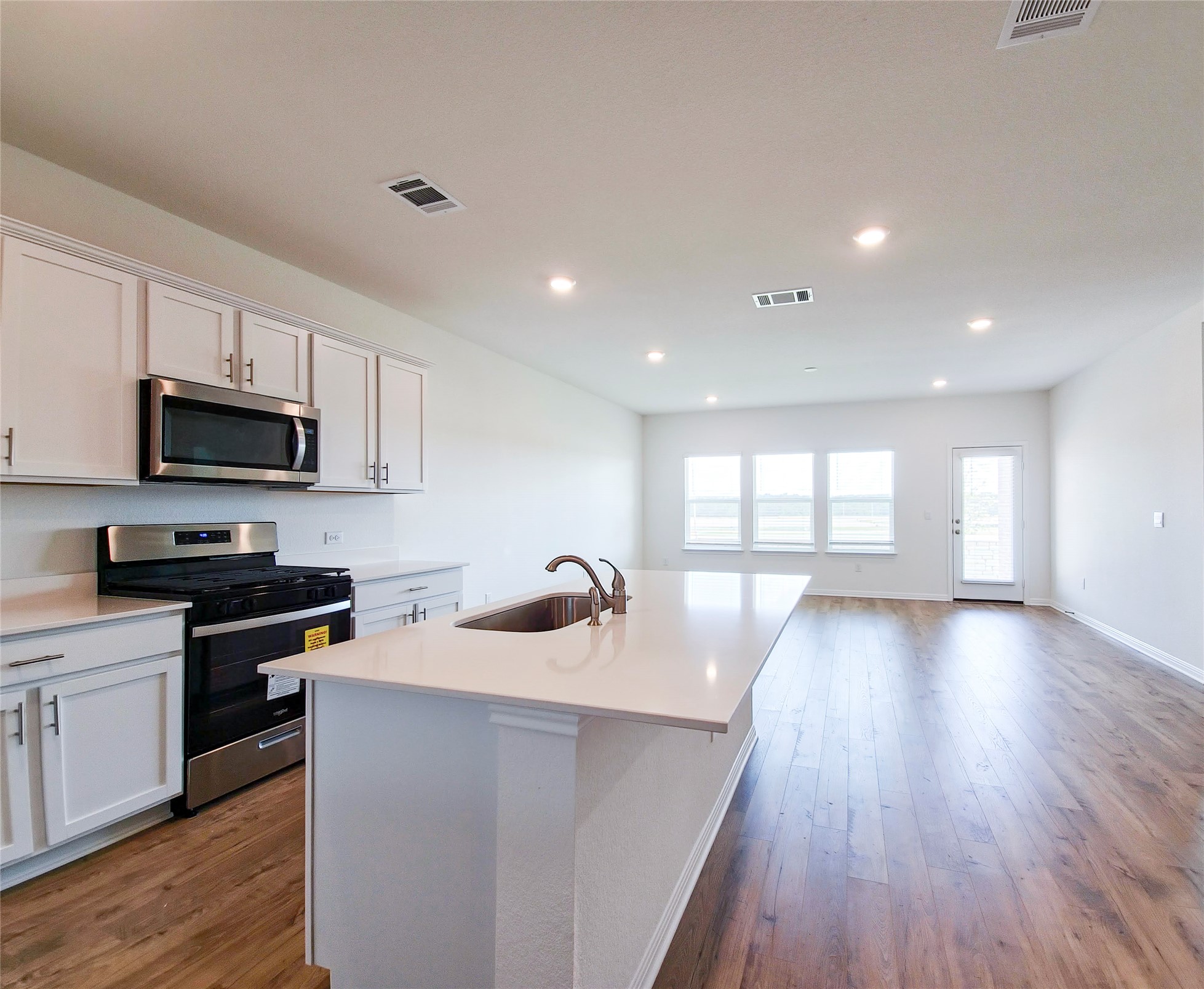 2313 March Hare Trace Leander, TX 78641 - Photo 15 of 30 Kitchen featuring stainless steel appliances, a kitchen island with sink, dark wood-style flooring, white cabinets, and light stone countertops