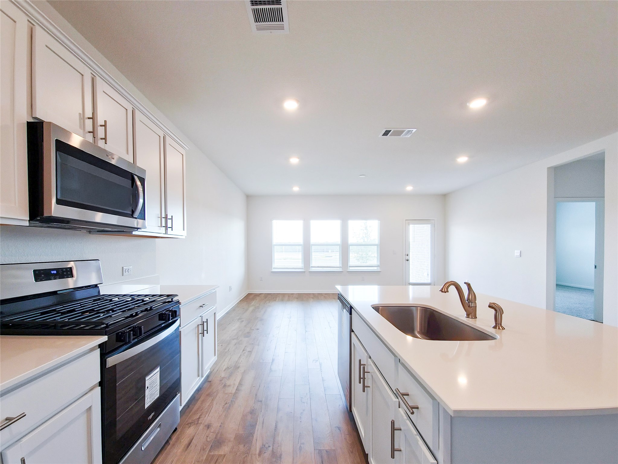 2313 March Hare Trace Leander, TX 78641 - Photo 9 of 30 Kitchen featuring stainless steel appliances, light wood-style flooring, a kitchen island with sink, white cabinetry, and recessed lighting