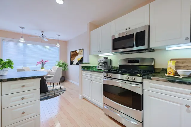 a kitchen with white cabinets stainless steel appliances and wooden floor