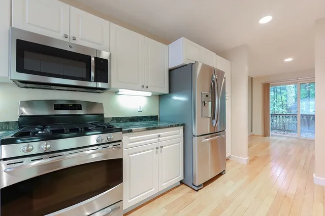 a kitchen with stainless steel appliances a stove a microwave and a hard wood floors