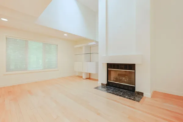 a view of empty room with wooden floor and fireplace