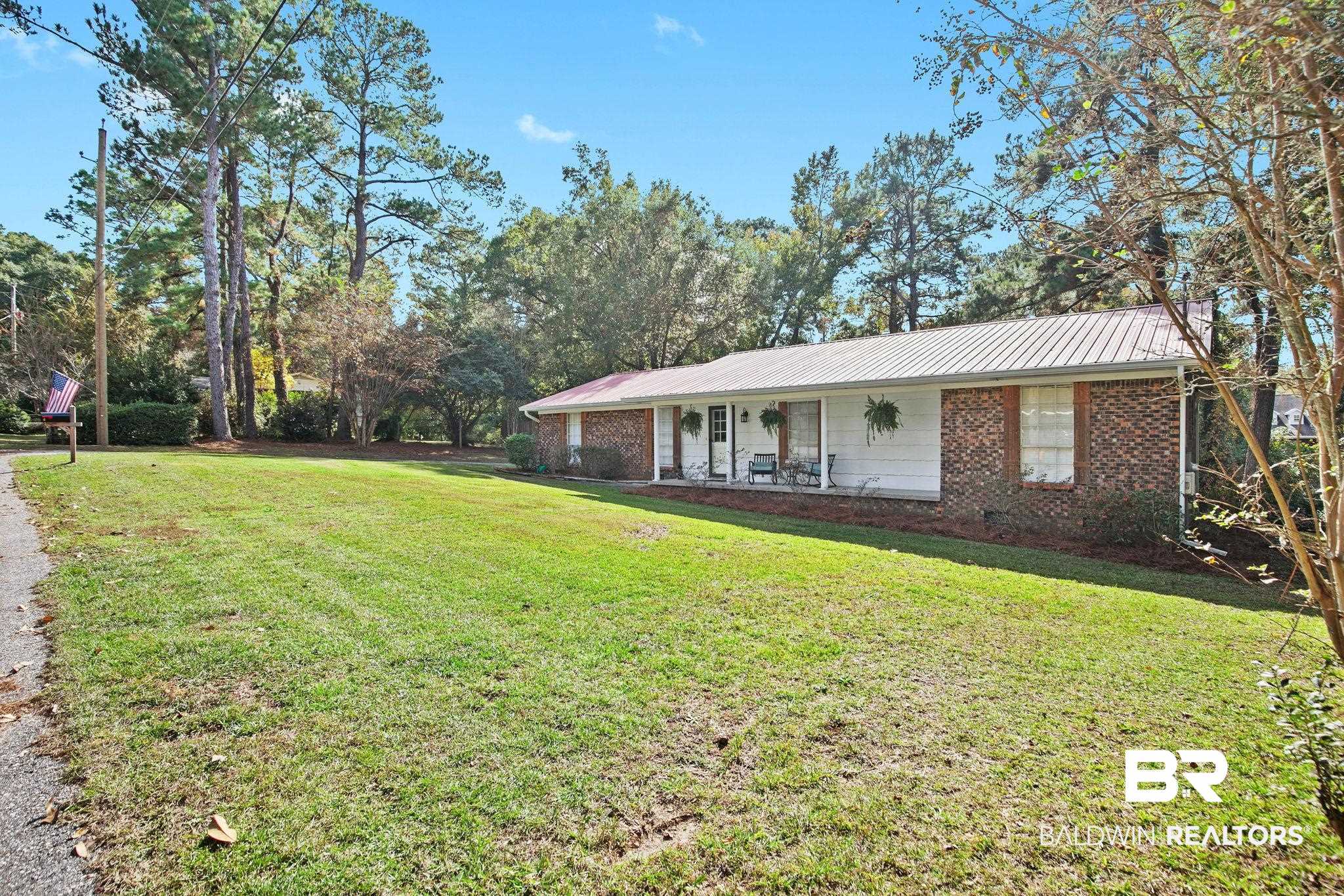 4 Rally Road Spanish Fort, AL 36527 - Photo 2 of 41 View of front of property featuring a metal roof, a front lawn, covered porch, and brick siding