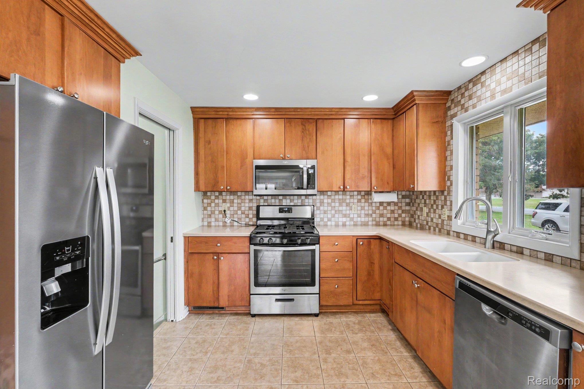 5199 Lapeer Road Burton, MI 48509 - Photo 9 of 19 Kitchen featuring wood-finish cabinetry, stainless steel appliances, tile backsplash, and light-toned countertops