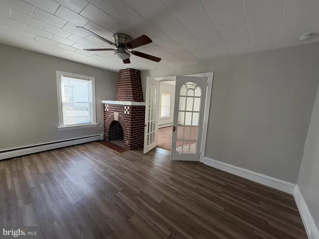an empty room with wooden floor fireplace and windows