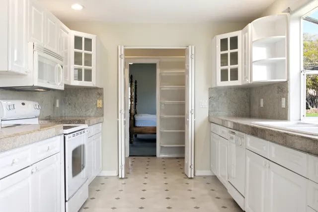 a kitchen with granite countertop white cabinets and white appliances