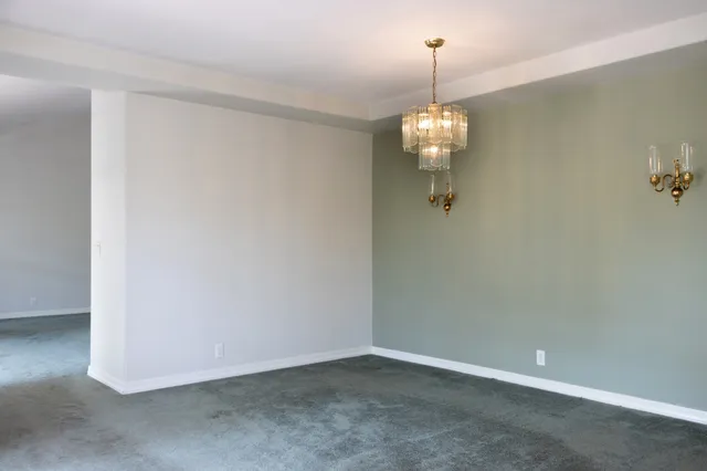a view of a hallway with wooden floor and a kitchen view