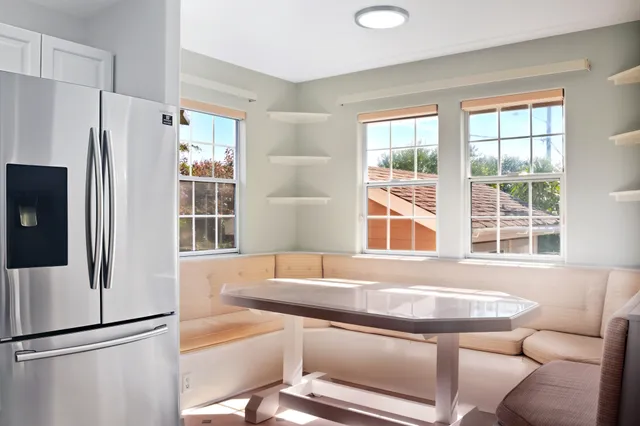 a living room with stainless steel appliances kitchen island granite countertop a large window and a counter space