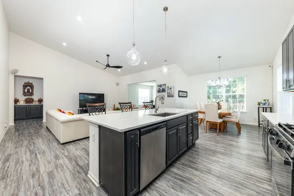 a large kitchen with kitchen island a white counter space a sink stainless steel appliances and cabinets