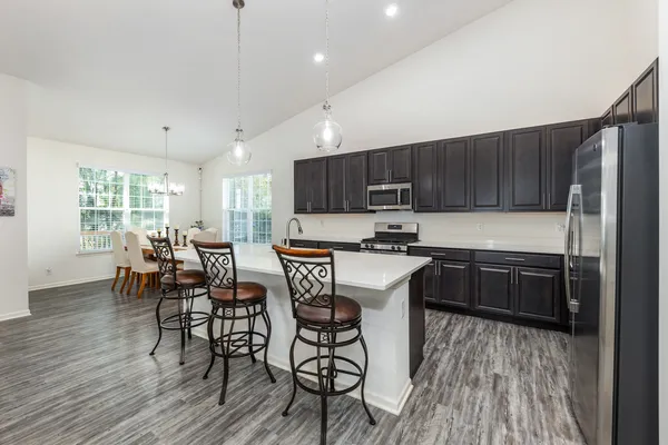 a kitchen with stainless steel appliances wooden floors wooden cabinets a center island and a window