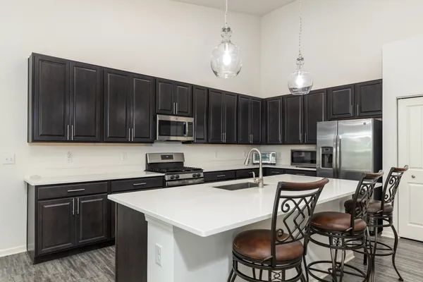 a kitchen with stainless steel appliances a stove a sink a microwave a refrigerator and chairs