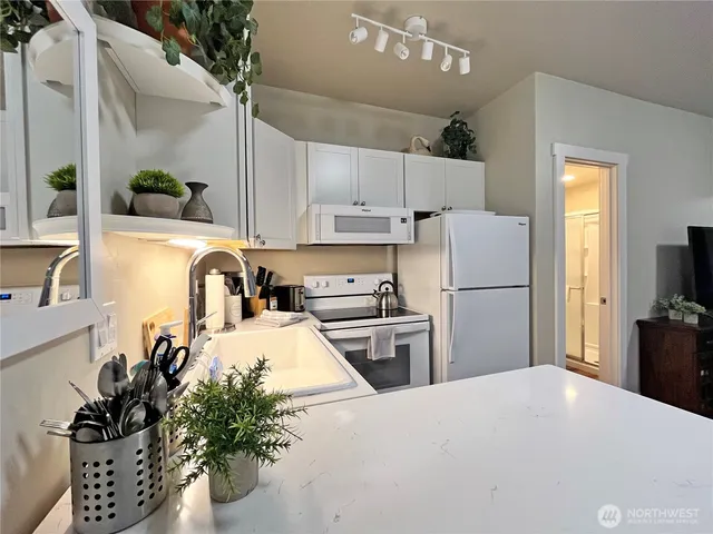 a kitchen with granite countertop a refrigerator a stove a sink dishwasher and a refrigerator with wooden floor