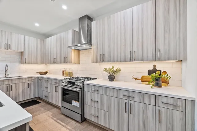 a kitchen with stainless steel appliances a stove a sink cabinets and a window