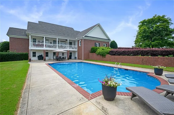a view of a house with pool fire pit a patio and a yard
