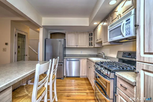 a kitchen with stainless steel appliances granite countertop a stove refrigerator sink and cabinets