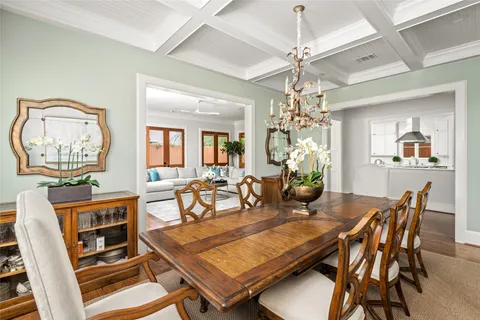 a dining room with wooden floor a chandelier a wooden table and chairs