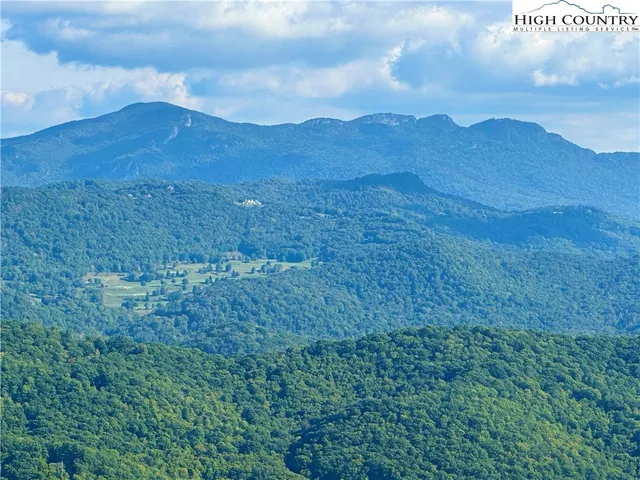 a view of a mountain range with lush green forest