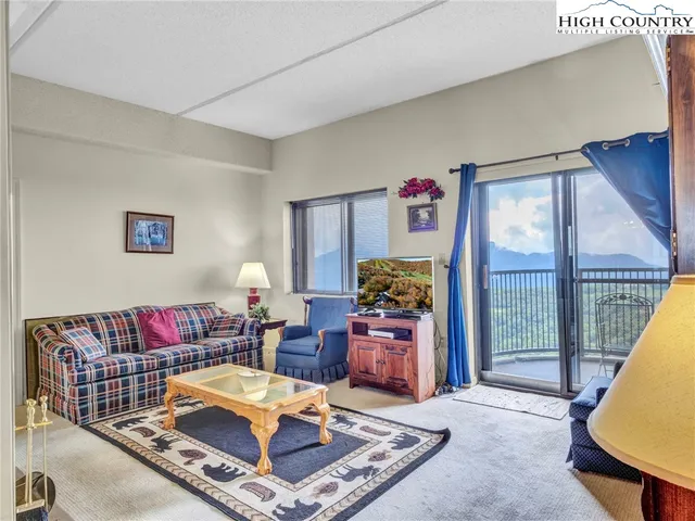 a living room with furniture a rug and a floor to ceiling window