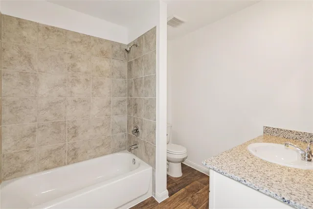 a bathroom with a granite countertop sink a toilet and bathtub