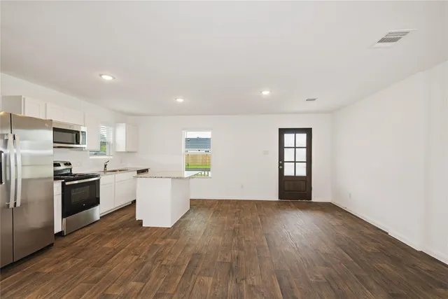 a large kitchen with a wooden floor and stainless steel appliances