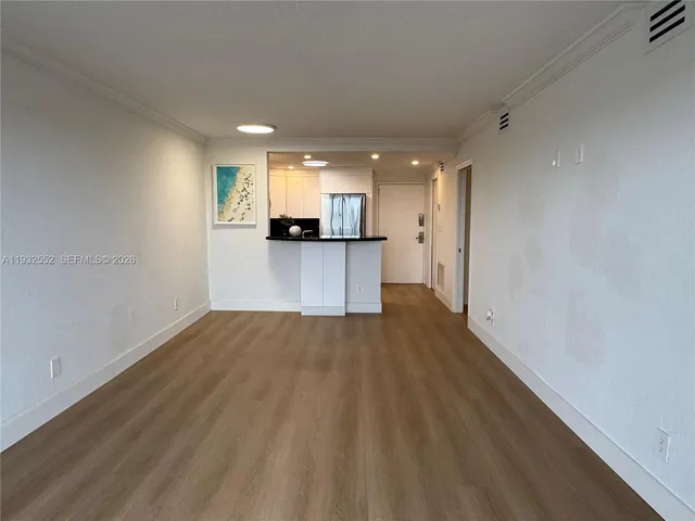 a view of a kitchen with a fridge and wooden floor